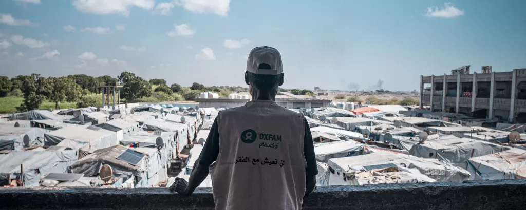 An Oxfam volunteer looks over a displacement camp