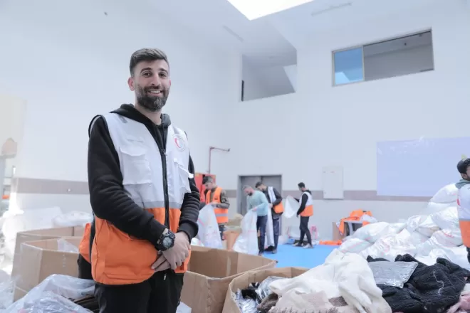 Man in charity vest stands in a warehouse at clothing distribution in Gaza