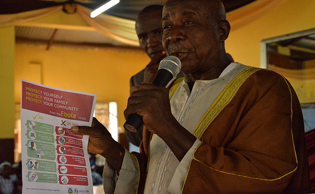 Alhaji Koker, chief district imam, holding a poster on Ebola prevention tips