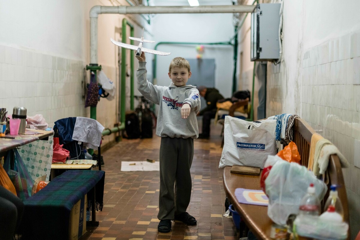 Boy plays with a toy plane in an underground bunker.