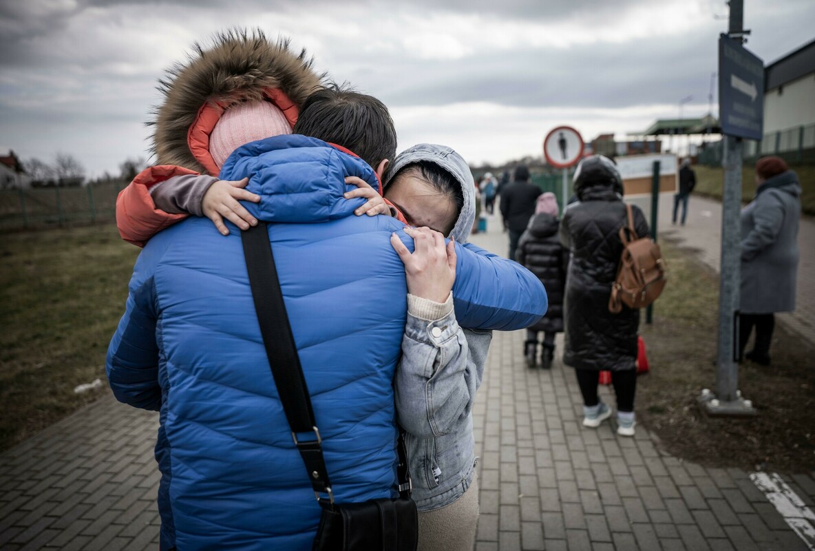 A man hugs his daughter and granddaughter after they crossed the border from Ukraine to Poland
