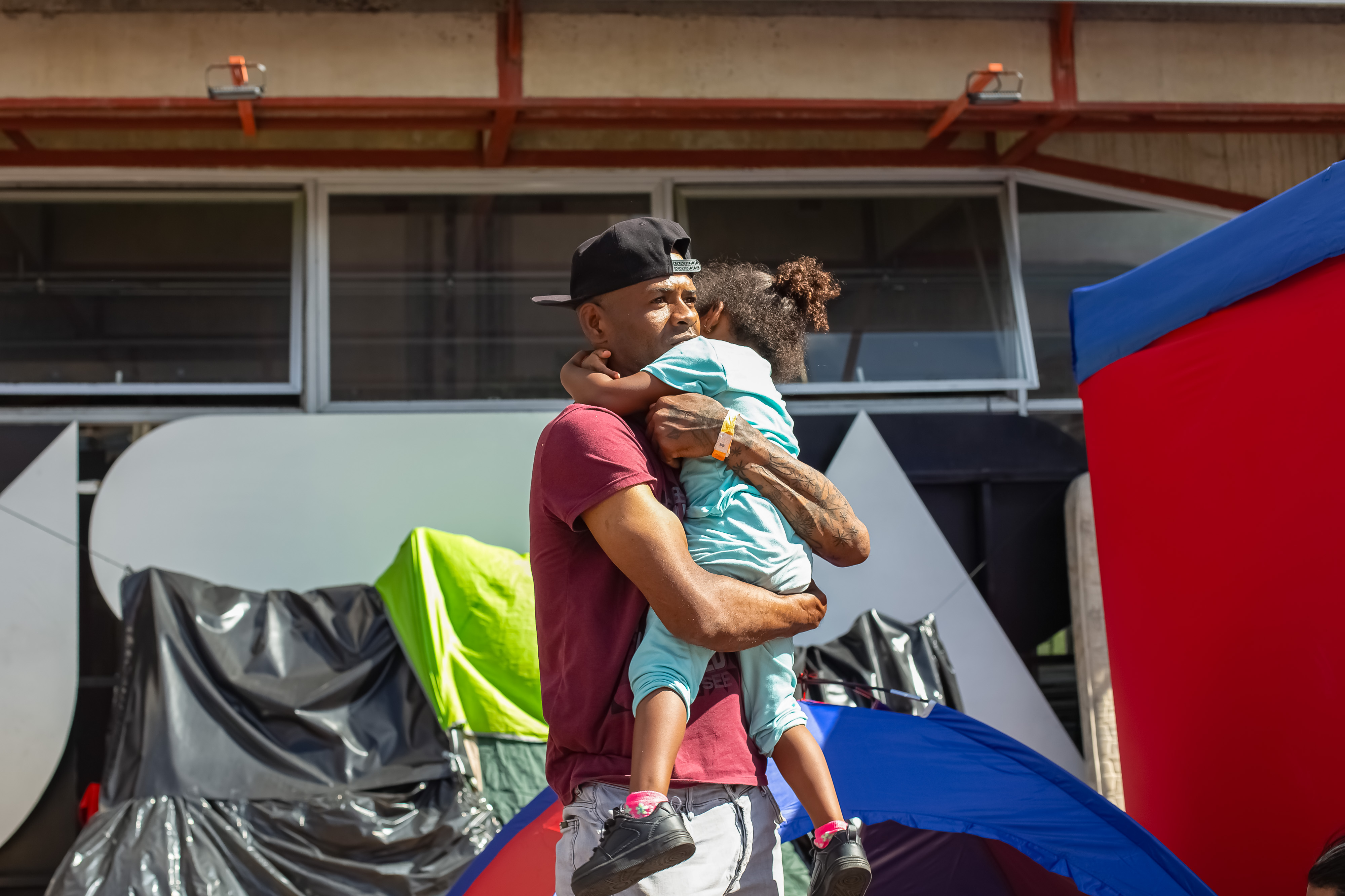 Man in Venezuela carries his daughter in tent camp
