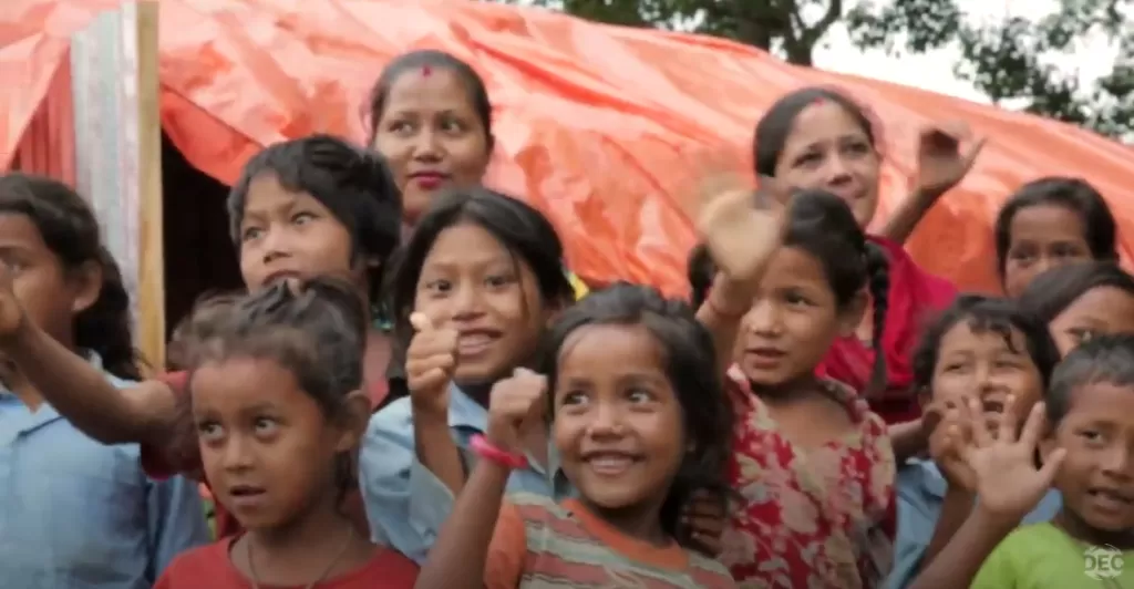 Children wave and give thumbs up signs