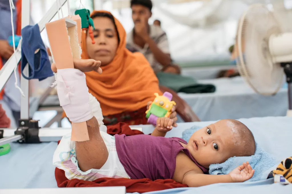 A baby lies on a hospital bed with his legs in traction