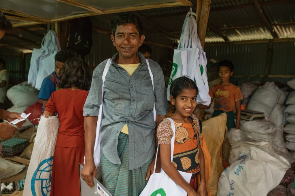 Sayed and his daughter collect fresh food from a DEC-funded voucher scheme, Moinerghona camp, Bangladesh.