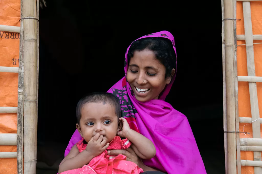 Sokina and her daughter sit in the doorway to their shelter in Moinerghona camp, Bangladesh.