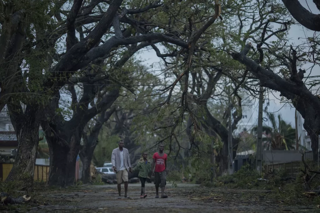People walk down a damaged street in a residential area of Beira, Mozambique after Cyclone Idai hit the city.