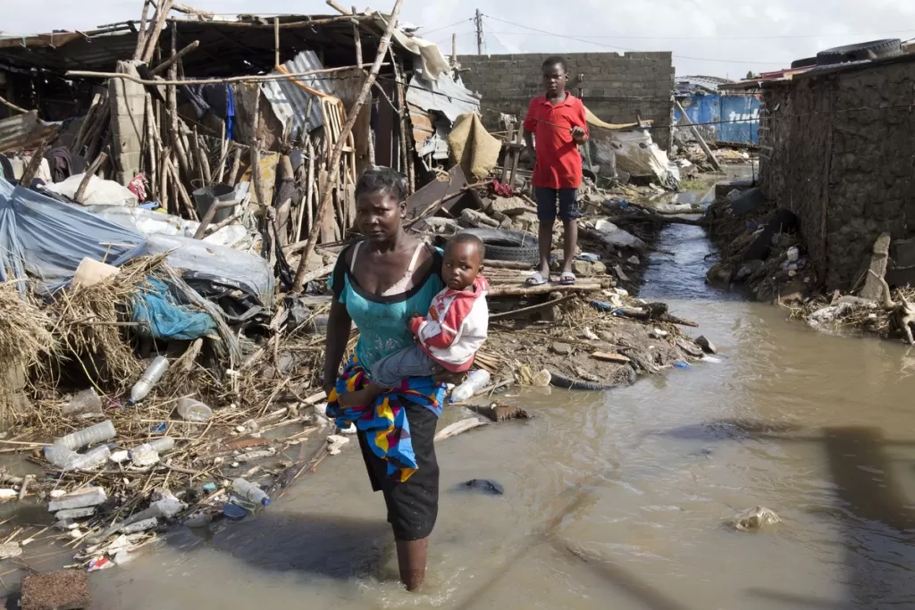 Clara holds her son as she walks through standing water near her house in Beira City, Mozambique.
