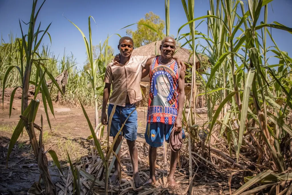 Fraction and George stand amid their damaged crops after returning to their village.