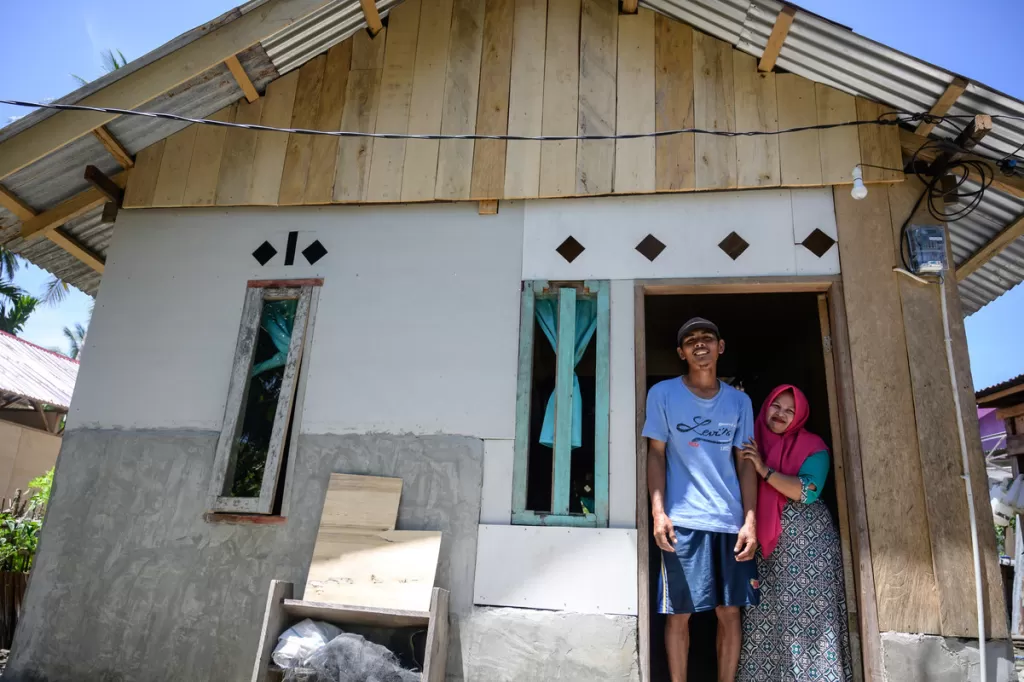 A couple stand in the doorway of their newly built house