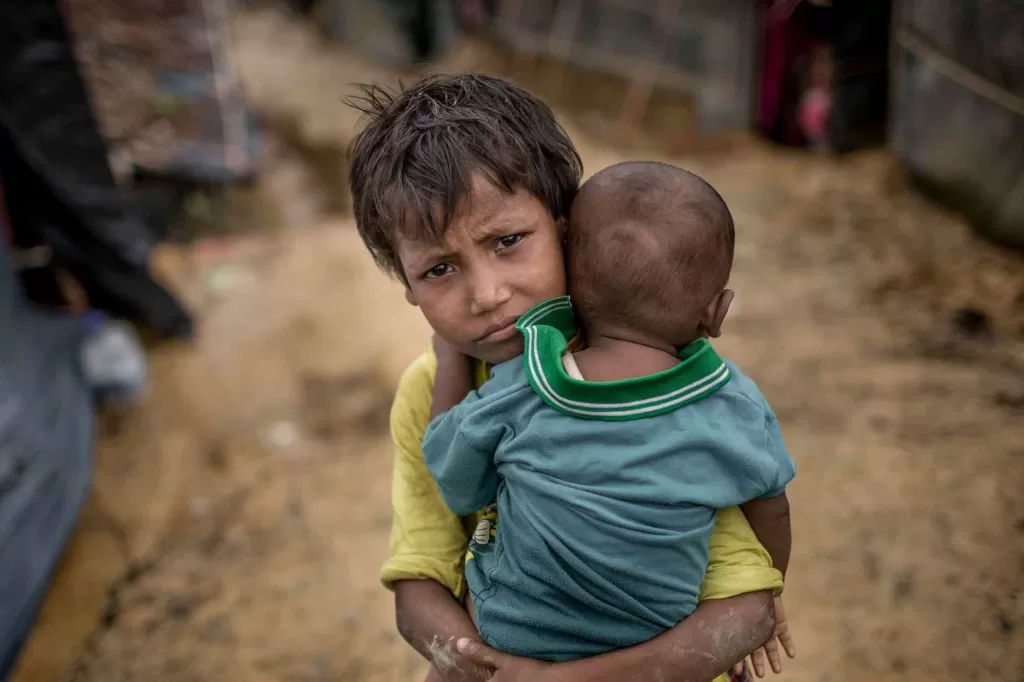 A girl carries her baby brother in the Rohingya refugee camps