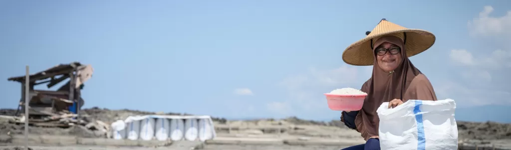 A woman packs salt into a sack to sell