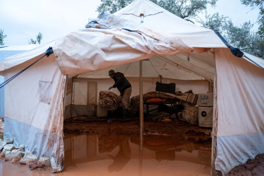 Abu Ahmad tries to clear water from his flooded tent in Al-Hilal camp after heavy rainstorms in January 2021