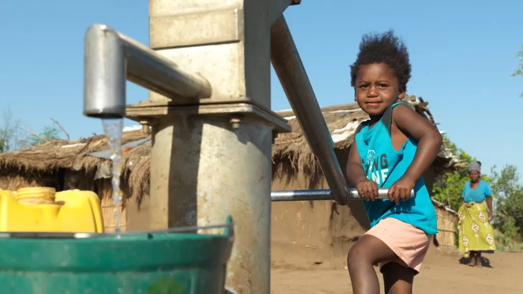 A child from Buzi, Mozambique, plays with a borehole rehabilitated by World Vision using DEC funds after it was damaged during Cyclone Idai.