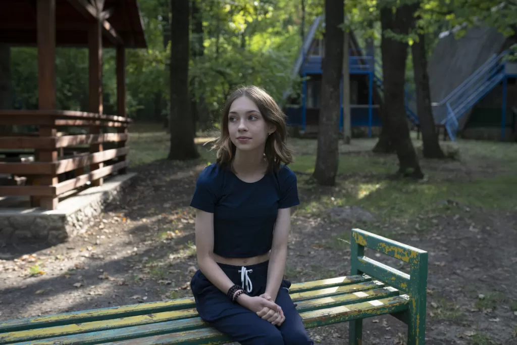 Anastasia sits on bench in a park