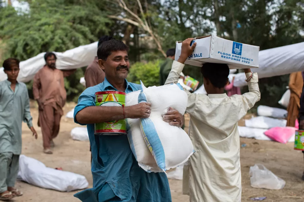 Flood affected people receive food aid from DEC charity Islamic Relief at a village in Sindh, Pakistan.