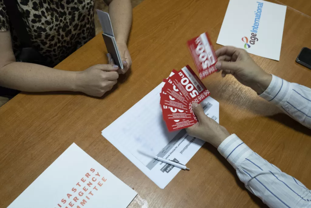 A Ukrainian refugee (left) receives DEC-funded cash vouchers delivered by Age International through its local partner HelpAge International in central Moldova, on August 11th 2022.