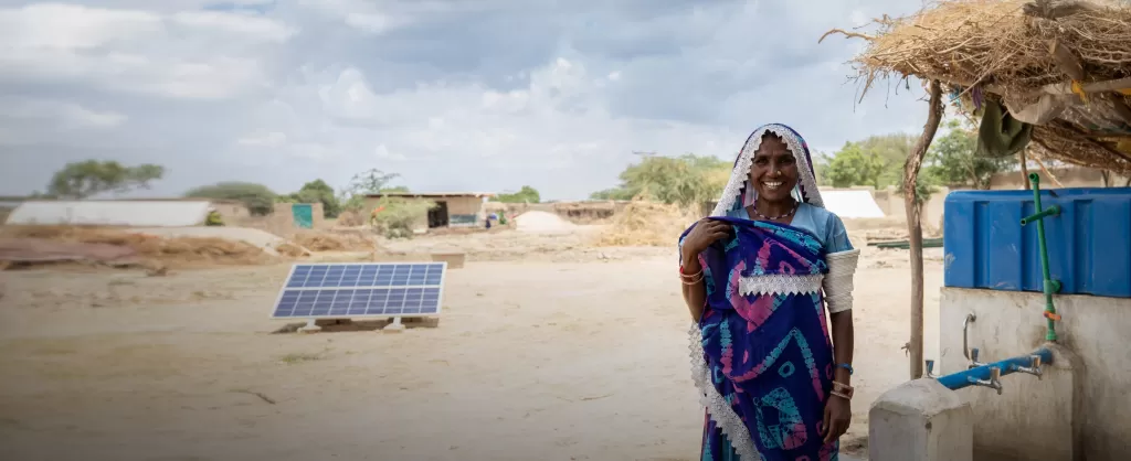 Lakshmi smiling with the solar panel water supply