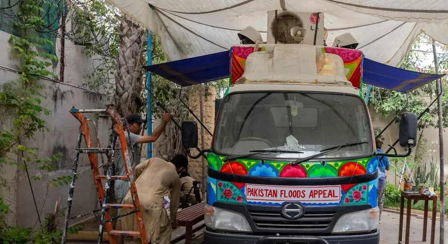 Artists work on painting the aid truck with appeal logo on the front