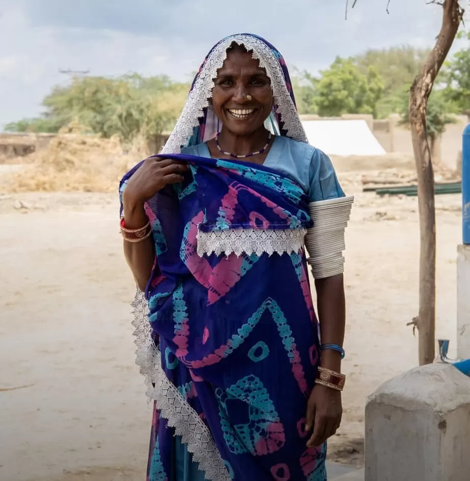 Lakshmi smiling with the solar panel water supply