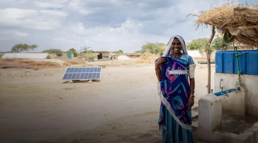 Lakshmi smiling with the solar panel water supply