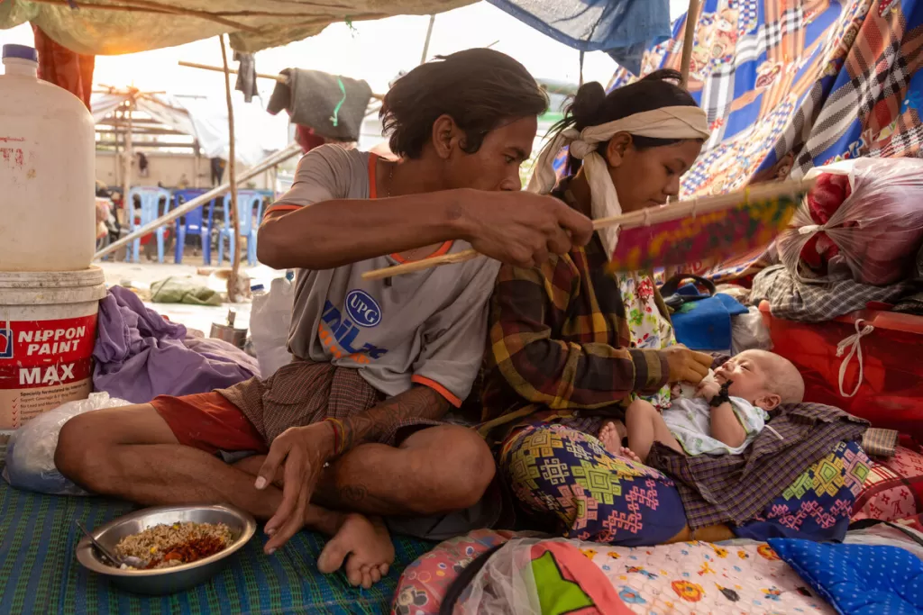 Women with tempory shelter in Myanmar fans her baby