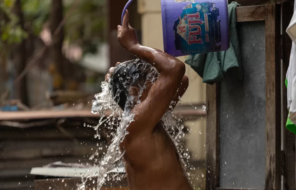 Boy pours water over his head from a bucket
