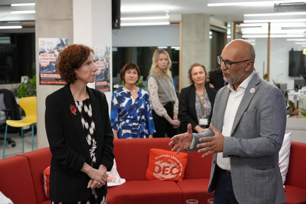 Anneliese Dodds, Minister for Development at the FCDO (at the time), speaks with DEC CEO Saleh Saeed at the DEC office on 29 October 2024. They are standing in discussion with DEC staff in the background.