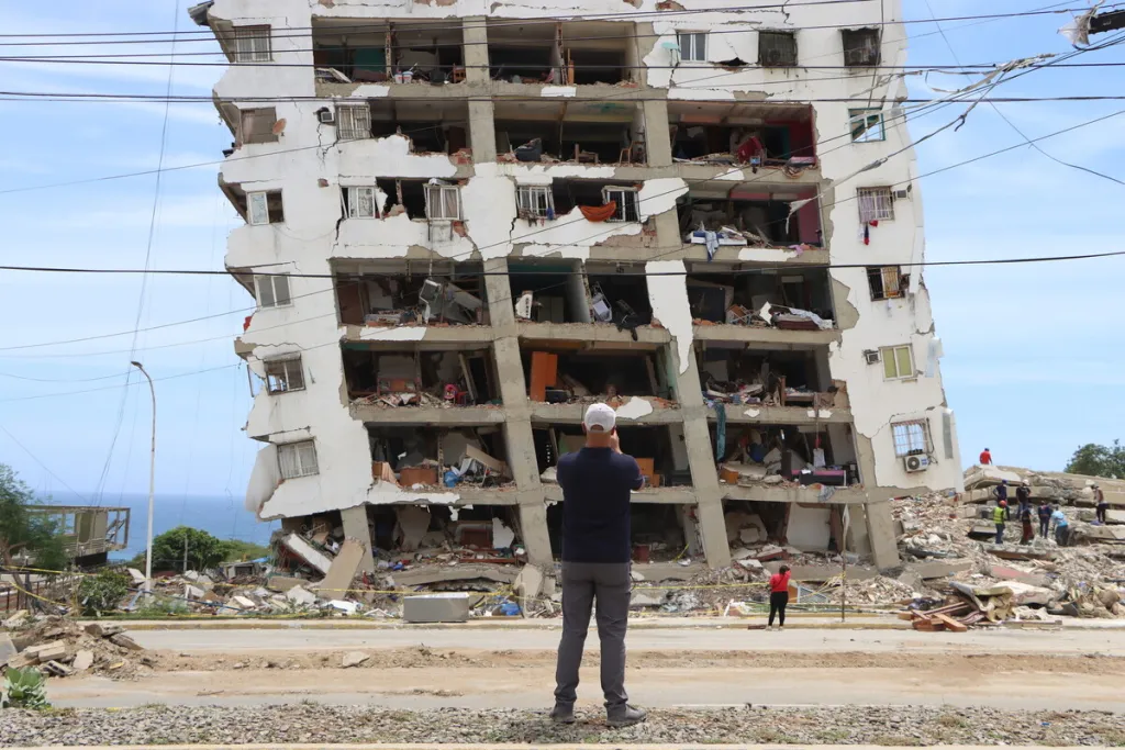 Man looks up at building destiryed by earthquake