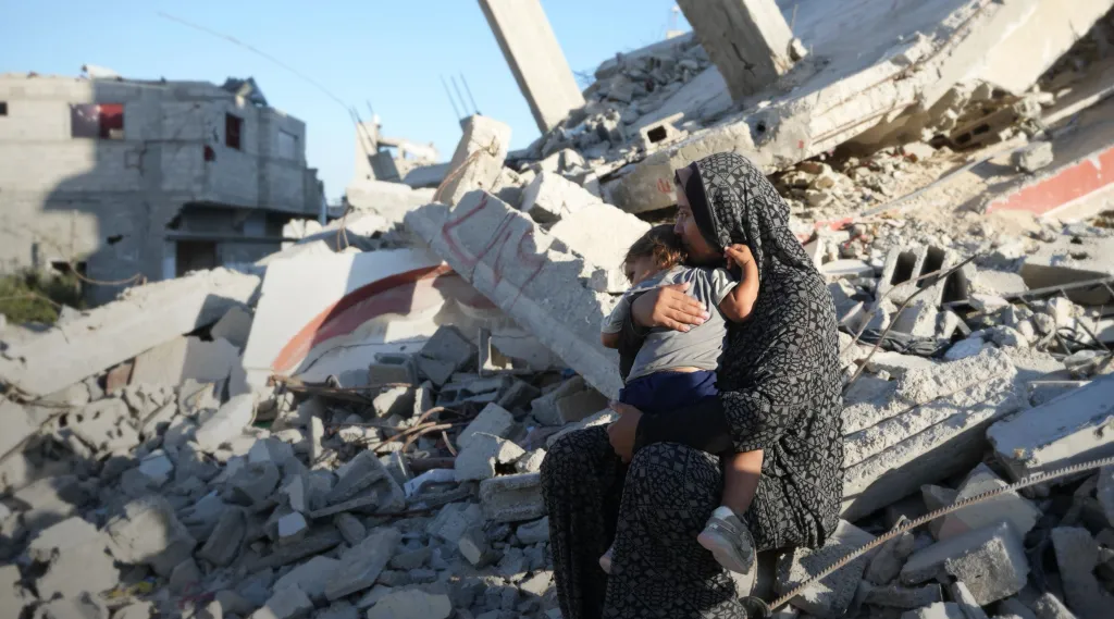 Aaliyah* holds her daughter on the remains of a damaged building in Gaza in October 2024. Photo: DEC/Arete/Abdallah Alsayed