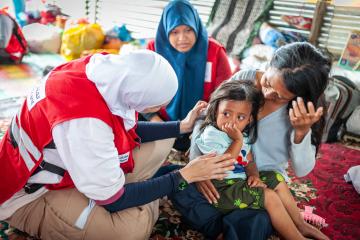 An aid worker comforts a child