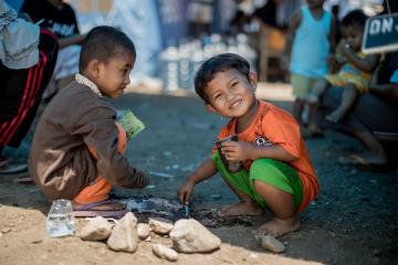 Two children make mud castles in Petobo camp