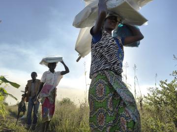 People carry tools and shelter materials after a distribution near Tica, Mozambique, three months after Cyclone Idai. 