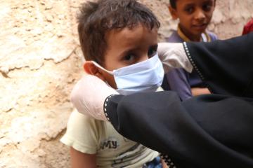A child is fitted with a mask at a hygiene training session run by CARE International in Yemen to help prevent the spread of coronavirus to vulnerable communites