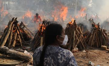 A family member looks on as several funeral pyres of those patients who died of COVID-19 disease burn up