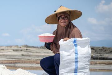 A woman packs salt into a sack to sell