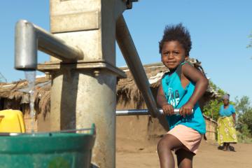 A child from Buzi, Mozambique, plays with a borehole rehabilitated by World Vision using DEC funds after it was damaged during Cyclone Idai.