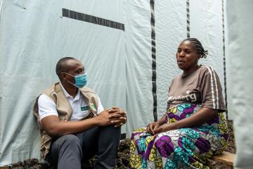 Hebdavi, aid worker, speaks to a camp resident near Goma where Tearfund has provided water, hygiene and sanitation.