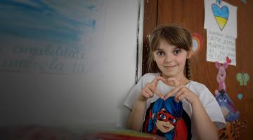 A girl who is a refugee from Ukraine makes a heart sign