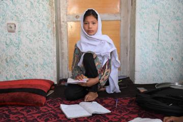 Fatima with her school books at home in Afghanistan