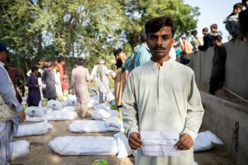 Shahjahan, 20, with a token that verified him in his hand to receive his food ration.