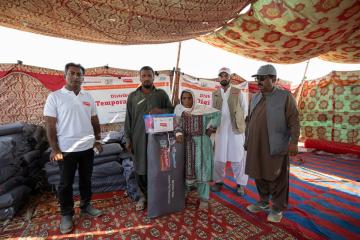 Ayesha stands with aid workers as she receives aid.