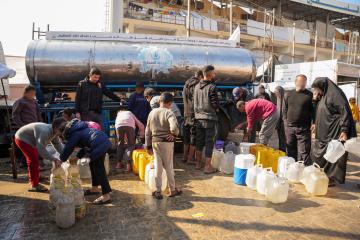 People queue with jerry cans to fill water from a truck in Gaza