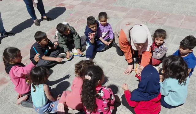 An aid worker from World Vision leads a session with children at a temporary shetler site 