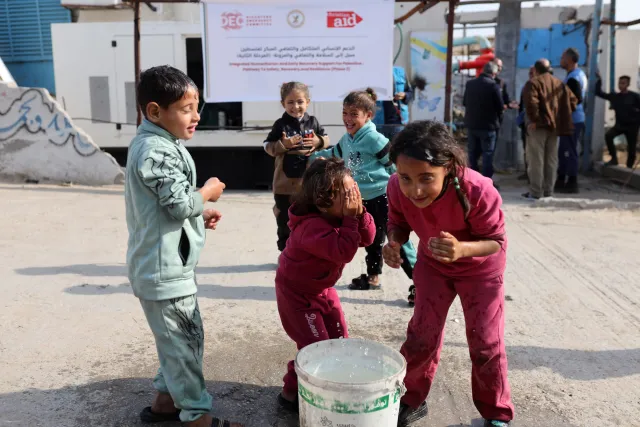 Children wash in water collected from a well supported by a local partner of DEC charity Christian Aid